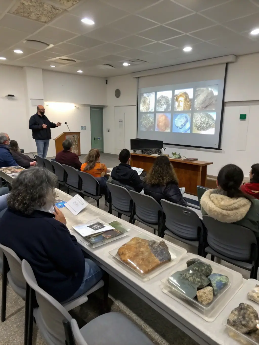 A classroom setting where participants are learning about geological mapping techniques, using maps, compasses, and other tools to understand terrain and mineral distribution.
